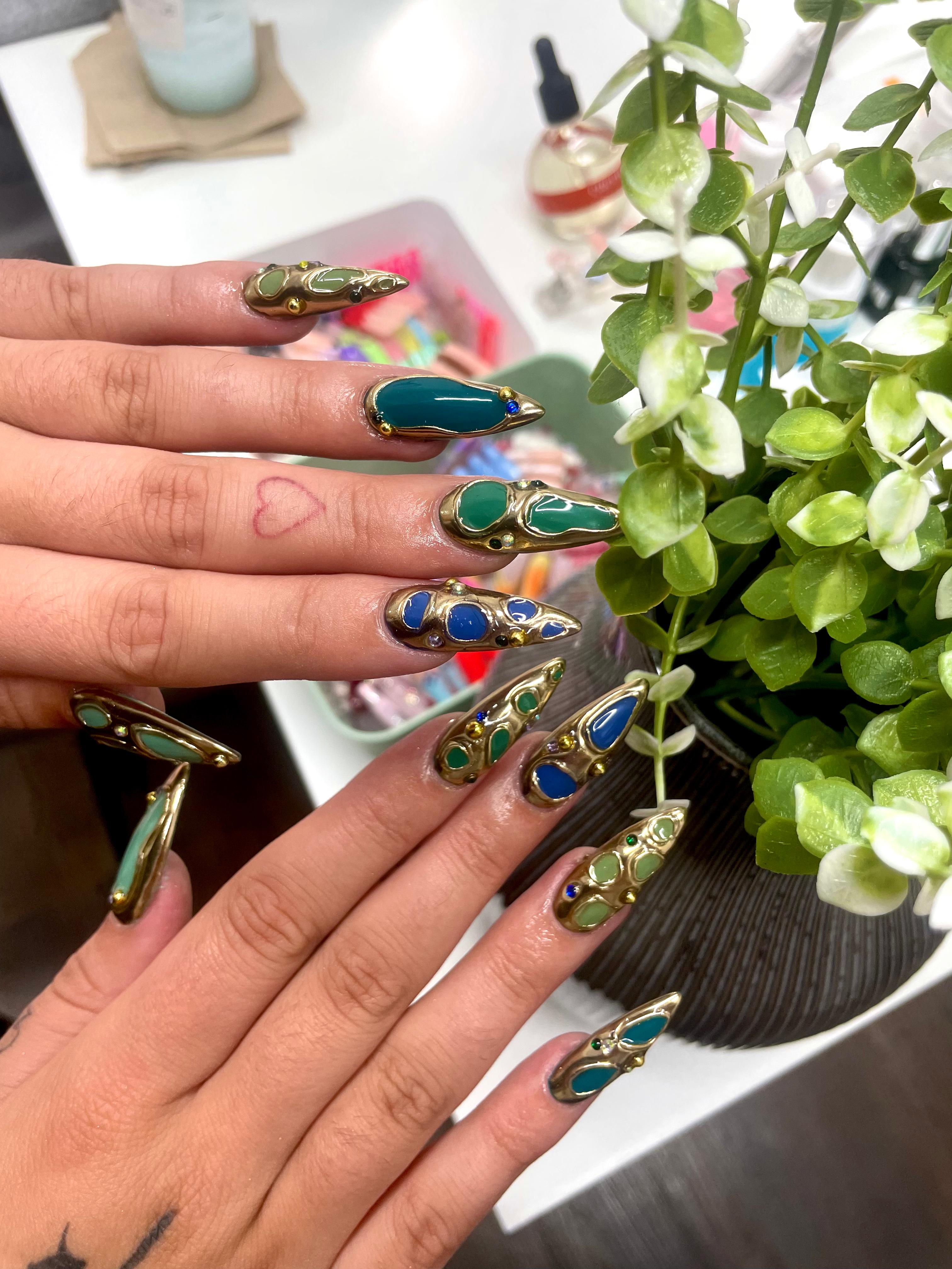 Jewel-toned nail art with gold accents by Jessica